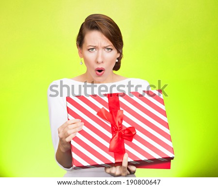 Closeup portrait young woman holding opening gift box, displeased, shocked angry disgusted with what received, isolated green background. Negative human emotion, facial expression, feeling, reaction