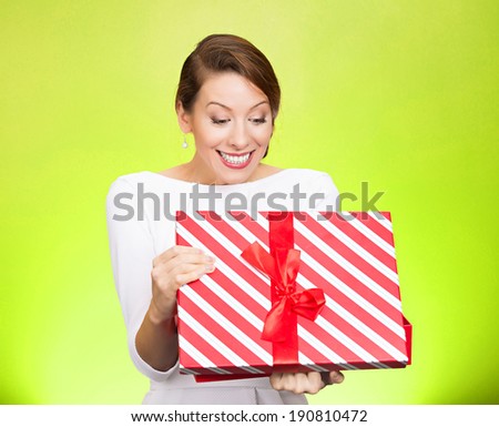 Closeup portrait happy looking super excited young woman lady unwrapping birthday gift box, isolated green background. Positive human emotion, facial expression, feeling, attitude reaction perception
