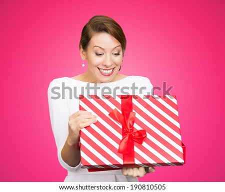 Closeup portrait happy looking super excited young woman lady unwrapping birthday gift box, isolated pink background. Positive human emotion, facial expression, feeling, attitude reaction perception