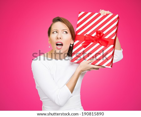 Closeup portrait happy, excited young woman about to unwrap red birthday gift box, wondering what is inside isolated pink background. Positive emotion, facial expression, feelings, attitude, reaction