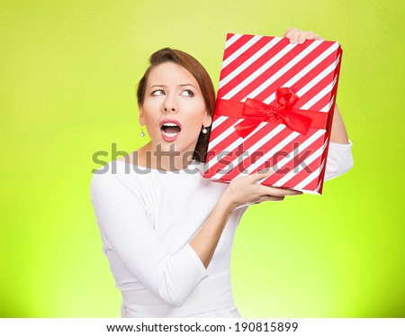 Closeup portrait happy, excited young woman about to unwrap red birthday gift box, wondering what is inside isolated green background. Positive emotion, facial expression, feelings, attitude, reaction