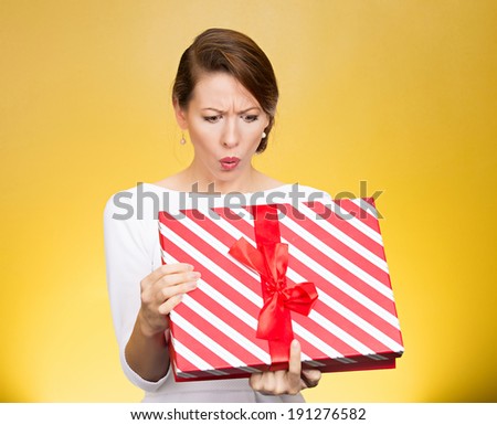 Closeup portrait young funny woman holding opening gift box, surprised, shocked with unexpected present received, isolated yellow background. Sudden human emotion, facial expression, feeling, reaction