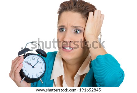 Closeup portrait, overwhelmed, busy, unhappy stressed female, anxious funny looking woman, student biting finger nails, running out of time, holding alarm clock exhausted, isolated white background.