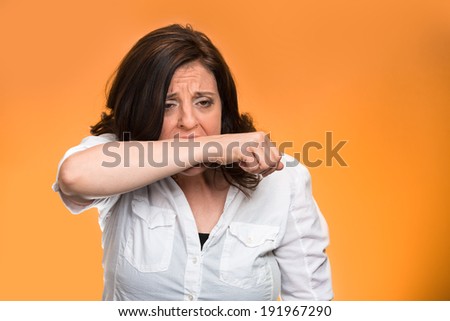 Closeup portrait crazy, angry, looney middle aged business woman, corporate worker employee going through stress, conflict in life biting her arm, isolated orange background. Negative human emotions.