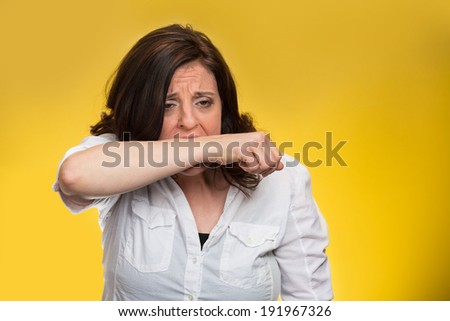 Closeup portrait crazy, angry, looney middle aged business woman, corporate worker employee going through stress, conflict in life biting her arm, isolated yellow background. Negative human emotions.