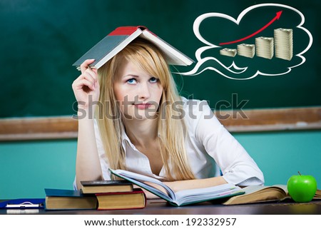 Closeup portrait business woman student teacher seating at desk thinking how make money looking worried isolated green chalkboard background, bubble filled with pile growing dollars. Facial expression