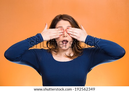 Closeup portrait, head shot young, coy woman, female closing eyes with hands can\'t see, hiding, mouth open, isolated orange background. See no evil concept. Negative emotion, facial expression feeling