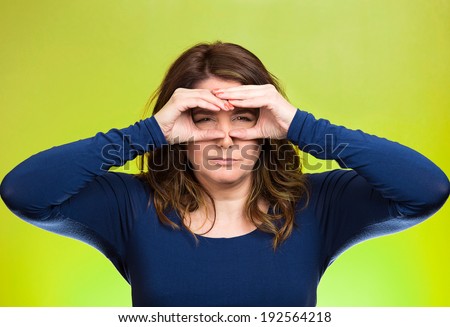 Closeup portrait young, curious funny woman, looking through fingers like binoculars, searching something, unhappy, disgusted with what waiting in future, isolated green background. Facial expressions