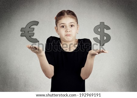 Closeup portrait confused, puzzled, funny looking little girl making scale with her arms checking Euro versus Dollar, not sure what choice to make, isolated grey black background . Facial expressions