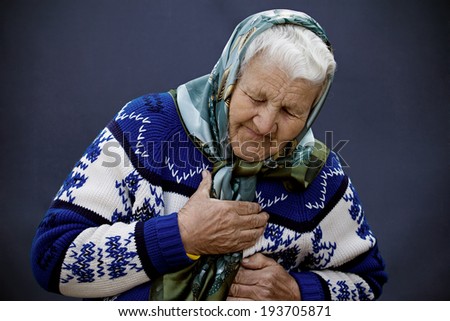 Closeup portrait elderly female, senior woman, grandmother having sudden chest, heart pain, trying catch air, isolated blue background. Myocardial infarction, aortic aneurysm rupture. Face expression