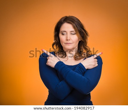 Closeup portrait confused young woman pointing in two different directions, not sure which way to go in life, isolated orange background. Negative emotions, facial expressions, feeling body language