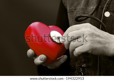 Closeup, cropped, black white portrait, picture hands of senior, elderly, man, grandfather holding, listening with stethoscope red heart isolated black background. Human emotions. Old people health.