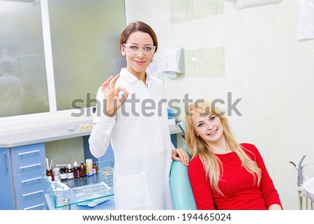 Closeup portrait happy female health care professional, dentist, satisfied smiling woman patient in office giving ok sign.