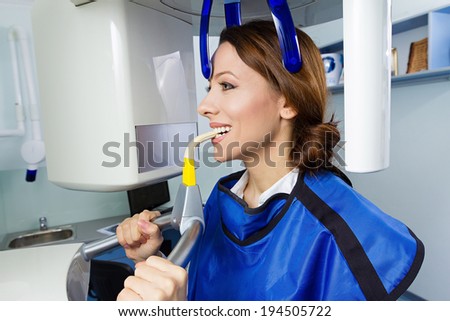 Closeup portrait young woman having panoramic digital X-ray of her teeth, isolated background dentist office.