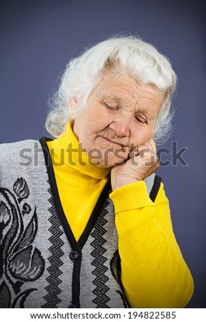 Closeup portrait headshot sleepy, tired, fatigued, low in energy, looking funny senior mature woman, laying face on hands, isolated blue background. Human facial expression, emotion, feelings reaction