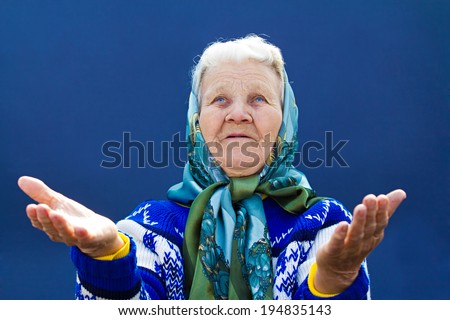Closeup portrait, senior mature, old woman praying, eyes opened, hands up in air apart, looking up, hoping best, asking forgiveness, miracle, isolated blue background. Human emotion, facial expression