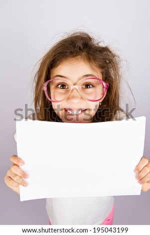 Closeup portrait smiling little, cute, funny looking girl with glasses holding blank piece of white paper isolated grey background. Positive human emotion, facial expression, reaction. Life perception