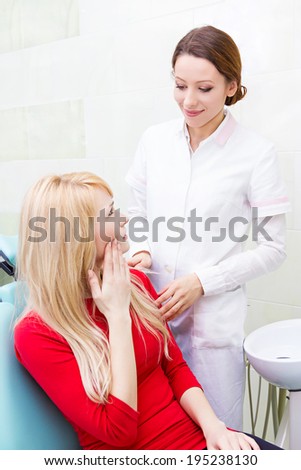 Closeup portrait sad girl, woman with painful tooth, ache in medical office siting in chair, explaining her problem to dentist isolated clinic office background. Face expressions, feelings, reaction