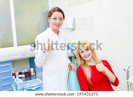 Closeup portrait happy female health care professional dentist, satisfied smiling woman patient in office giving thumbs up sign gesture. Successful treatment procedure, care, outcome. Positive emotion