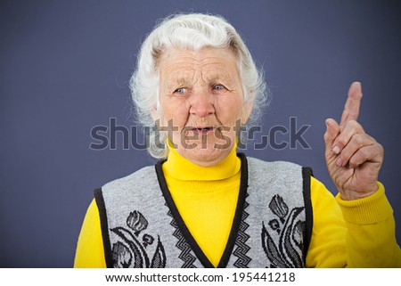 Closeup portrait senior mature smiling woman pointing with index finger hand upwards, one sign, got idea isolated blue background. Positive thinking. Emotions, facial expressions, symbols, reaction