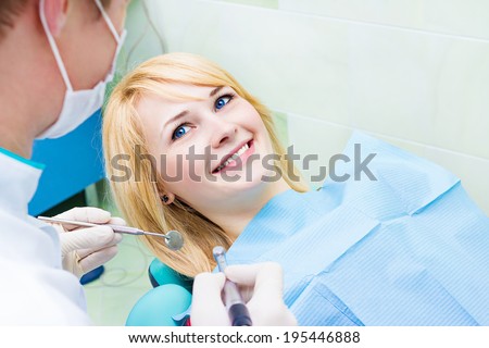 Closeup portrait smiling happy patient in dentist office, doctor holding angled mirror ready to examine teeth oral cavity. Clinic visit, preventive medicine annual check up. Positive facial expression