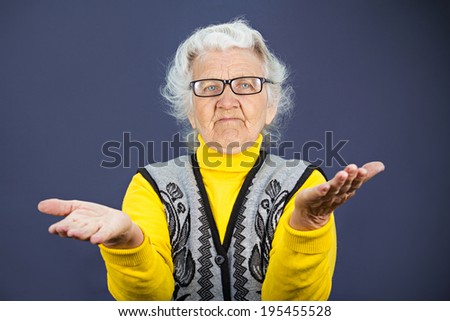 Closeup portrait, clueless senior, mature, elderly woman, arms out asking why whats problem who cares so what I don\'t know, isolated blue background. Negative human emotion, facial expression feeling