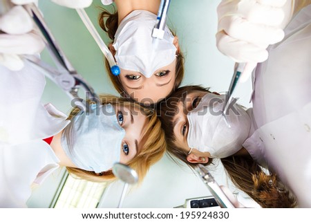 View of doctors dentists holding surgical instruments by patient after operation on background of lamp ceiling Patient hospital intensive care unit visit emergency hospitalization View of doctors dentists holding surgical instruments by patient after operation on background of lamp ceiling Patient hospital intensive care unit visit emergency hospitalization