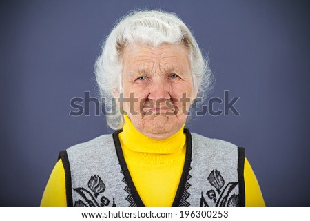 Closeup portrait, headshot, unhappy, grumpy, skeptical, sad, senior woman about to cry, looking at you isolated blue background. Negative human emotions, facial expressions, feelings, life perception