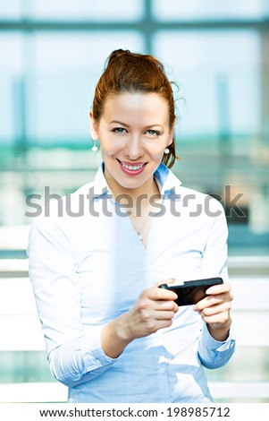 Closeup portrait, happy, cheerful, excited girl, using cell phone, isolated background corporate office. Facial expression, reaction. Business woman sending text message from her mobile. Technology