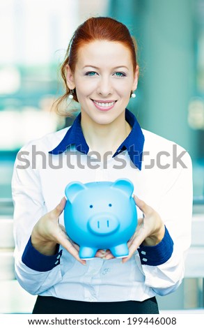 Closeup portrait happy, smiling business woman, bank employee holding piggy bank  isolated background corporate office windows. Financial savings concept. Positive human emotions, facial expressions