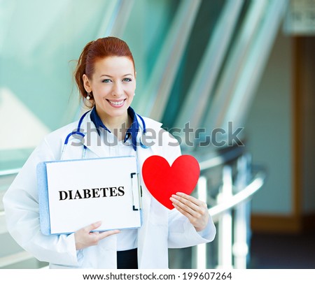 Closeup portrait happy smiling female health care professional, woman family doctor, cardiologist with stethoscope holding sign diabetes, heart isolated hospital hallway background. Patient plan