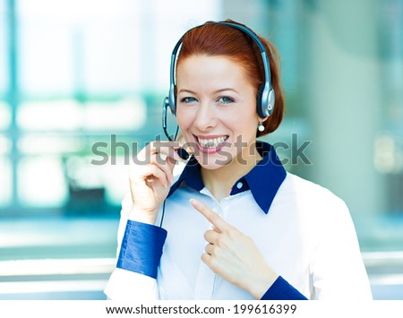 Closeup portrait young happy successful business woman, customer service representative, call centre worker, operator, support staff speaking with head set isolated background corporate office windows