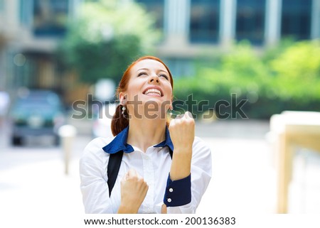 Closeup portrait happy smiling business woman with arms up, excited pumping fists, celebrating isolated background outdoors corporate office. Positive human emotion, facial expression feeling reaction