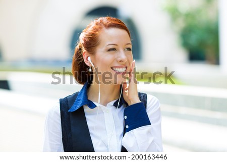 Closeup portrait attractive happy, smiling business woman walking on street listening to music outdoors, laughing isolated city background. Positive human emotions, facial expressions, life perception