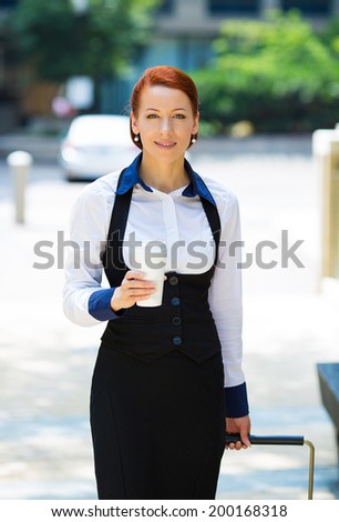 Business woman going on trip. Portrait businesswoman, company employee, attractive corporate executive, young model crossing street, traveling with luggage, handbags in the city, holding cup of coffee