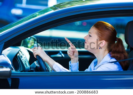 Closeup portrait displeased angry pissed off aggressive woman driving car, shouting at someone, hands up in air isolated traffic background. Emotional intelligence concept. Negative human expression
