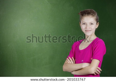 Closeup portrait thinking confident young, happy, smiling  student girl, woman by green chalkboard background, arms crossed, high school pupil, contemplating looking at you. Positive face expressions