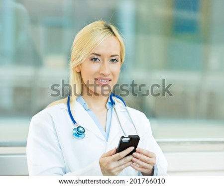Closeup portrait young healthcare professional, doctor, nurse, dentist, researcher, physician assistant reading text sms, message on cellphone holding smart phone isolated hospital hallway  background