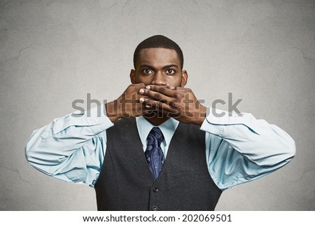Closeup portrait, silent young business man covering closed mouth observing. Speak no evil concept, isolated black background. Negative human emotion, facial expression sign symbol. Media news coverup