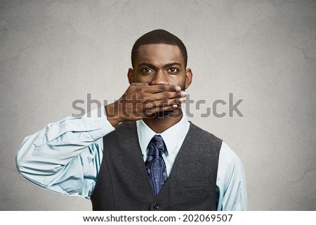 Closeup portrait, silent young business man covering closed mouth observing. Speak no evil concept, isolated black background. Negative human emotion, facial expression sign symbol. Media news coverup