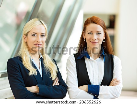 Closeup portrait two young beautiful, happy business women, confident company employees smiling isolated corporate office background. Positive human emotion, facial expression attitude life perception