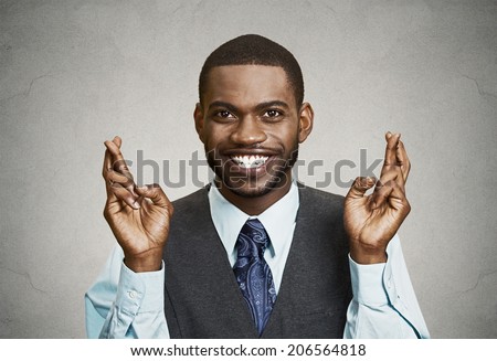 Closeup portrait young funny guy, business man crossing fingers, wishing, hoping for best, miracle isolated black, grey background. Positive human emotions, facial expressions, feelings, attitude