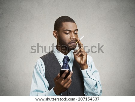 Closeup portrait serious worried business man, executive reading breaking news on smart phone holding mobile, smoking cigarette isolated black background. Human face expression, emotions body language