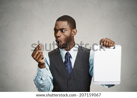 Closeup portrait upset man, guy says no to smoking, screaming at cigarette, holding notepad with blank paper copy space provided isolated black background. Healthy life choices. Passive smoking danger
