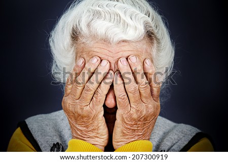 Closeup portrait sad depressed, stressed, thoughtful, senior, old woman, gloomy, worried, covering her face, isolated black background. Human face expressions, emotion, feelings, reaction, attitude