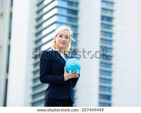Closeup portrait happy, smiling business woman, bank employee holding piggy bank, isolated outdoors corporate office background. Financial savings, banking concept. Positive emotions, face expressions