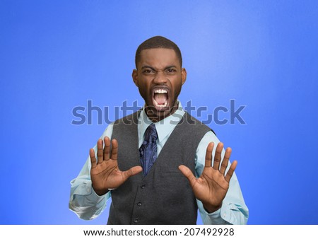 Closeup portrait furious angry annoyed displeased young man raising hands up to say no stop right there isolated blue background. Negative human emotion facial expression sign symbol body language
