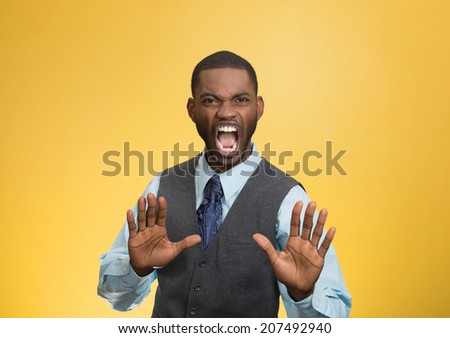 Closeup portrait furious angry annoyed displeased young man raising hands up to say no stop right there isolated yellow background. Negative human emotion facial expression sign symbol body language