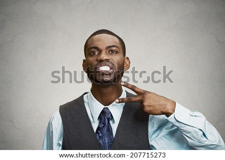 Closeup portrait, angry, mad young executive man gesturing with hand to stop talking, cut it out, or he will take your head off isolated grey background. Negative emotion, facial expression feelings