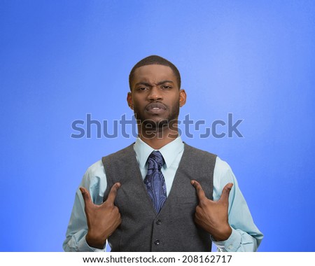 Closeup portrait angry, unhappy annoyed, rude young executive man, getting mad asking question you talking to, mean me? Isolated blue background. Negative emotion facial expression feeling attitude